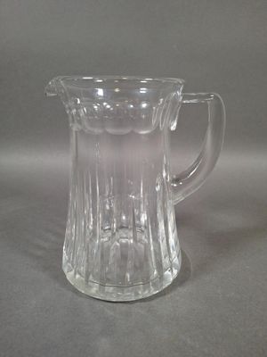 un pichet en verre posé sur une table, sur fond gris