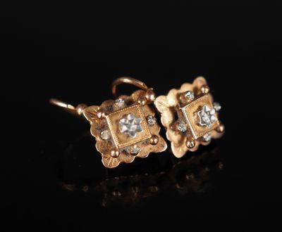 une paire de boucles d'oreilles en or et diamants sur une surface noire