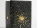 un livre noir orné d'étoiles dorées, posé sur une surface blanche