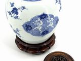 a blue and white vase sitting on a stand next to a wooden lid