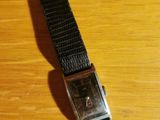 the watch is sitting on a wooden table with a black strap