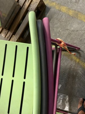une personne assise sur une chaise verte à côté d'une pile de chaises en plastique