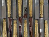 a lot of silver and gold spoons and knives in a box