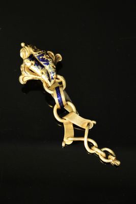 a gold and blue brooch with a dragon on it