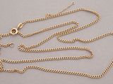 a close up of a gold chain on a gray surface
