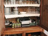 a wooden cabinet with many dishes and glasses on it