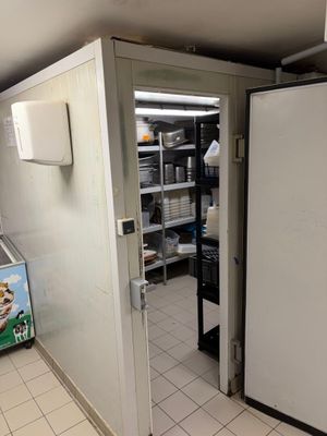 un réfrigérateur blanc dans une cuisine au sol carrelé de blanc