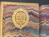 an open book with a gold medallion on the front of it