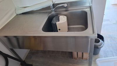 a stainless steel sink and a trash can in the kitchen
