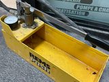 une boîte à outils jaune posée par terre près d'une fenêtre