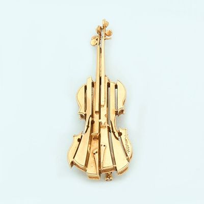 a gold violin brooch on a white surface