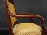 a close up of a wooden chair with a yellow upholstered cushion
