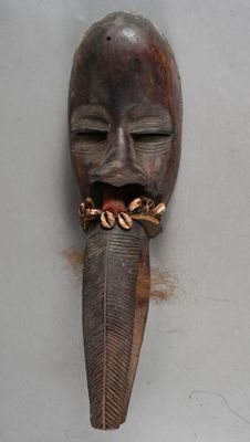 a wooden mask hanging on a wall with a chain around it