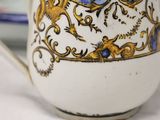 a white cup with a blue and gold design on it