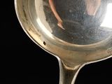 a silver spoon with a reflection of a person in it