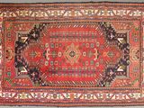 un vieux tapis à fond rouge et orné d'un motif