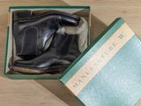 black leather boots in a green box on a wooden floor