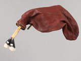 a hand holding a brush and a bag hanging from a string