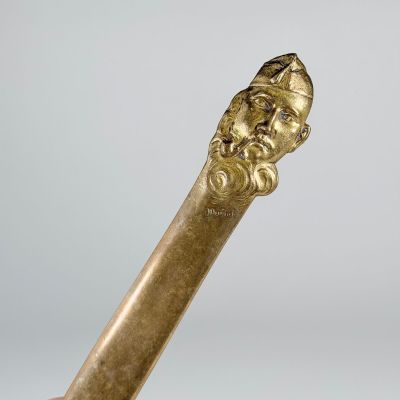a gold stick with a head of a man on it