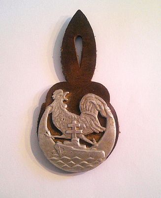 a metal pendant with a bird on it on a white surface