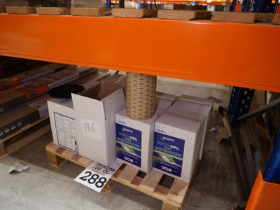 Les cartons sont empilés sur des palettes dans un entrepôt ; une étiquette est apposée sur chaque palette.