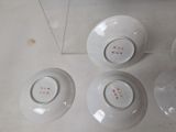 four white bowls with red spots on them sit on a white surface