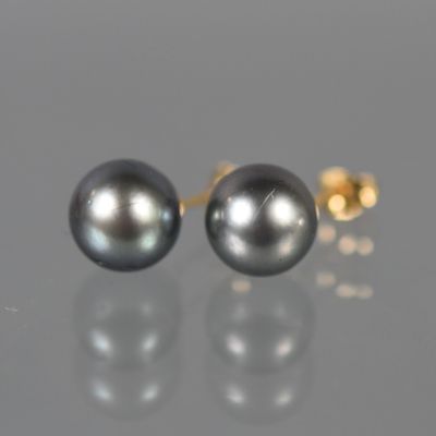 une paire de boucles d'oreilles en perles noires posées sur une surface réfléchissante