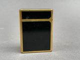 a close up of a black and gold lighter on a white surface