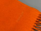une écharpe orange avec des franges, posée sur une table