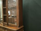 a wooden china cabinet with glass doors in a room