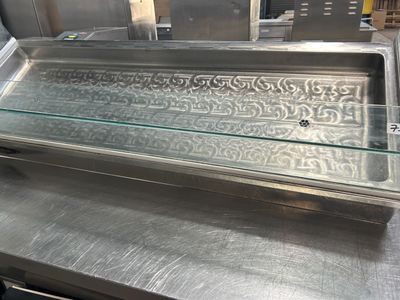 un plan de travail en acier inoxydable surmonté d'une vitrine en verre