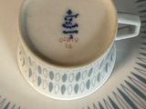 une tasse et une soucoupe posées sur une soucoupe sur laquelle est inscrit un nom