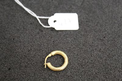 un gros plan d'une boucle d'oreille en or à laquelle est accrochée une étiquette