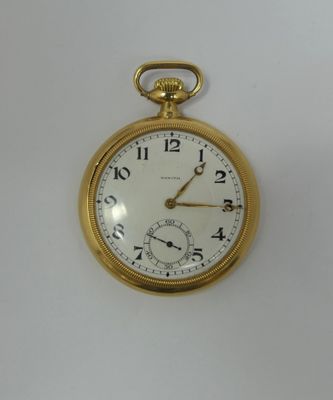 a close up of a gold pocket watch on a white surface