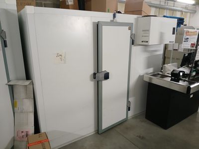 plusieurs réfrigérateurs et congélateurs dans un entrepôt rempli de cartons et encore de cartons