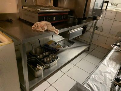 un plan de travail en acier inoxydable sur lequel sont posés des casseroles et des poêles, dans une cuisine professionnelle