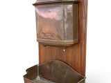 a wooden wall mounted water fountain with a metal container