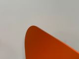 une chaise orange dans une pièce aux murs blancs