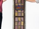 two people standing next to a tall stained glass window in a room