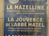 une enseigne bleue et blanche accrochée au mur d'un immeuble, sur laquelle figure l'image d'un homme coiffé d'un chapeau
