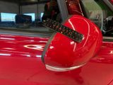 a red car with a sticker on it ' s side mirror