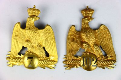 deux insignes représentant un aigle doré sur fond blanc, surmontés d'une couronne