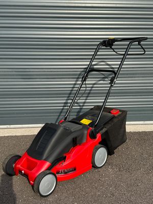 une photo d'une tondeuse à gazon rouge garée devant la porte d'un garage