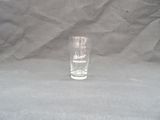 a shot glass sitting on a table with a gray background