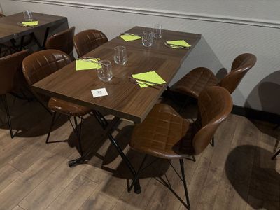 Des tables et des chaises sont alignées dans une pièce, avec un mur en arrière-plan.