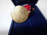 a gold medal with a red ribbon in a blue box