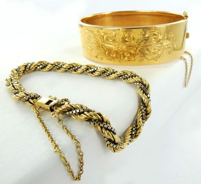 deux bracelets en or et un bracelet en or muni d'une chaîne, posés sur un fond blanc
