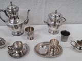 un service à thé en argent posé sur une table, avec des tasses et des soucoupes en argent
