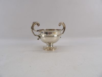 une coupe ancienne en métal argenté posée sur une surface blanche