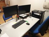 a desk with two computer monitors and a printer on it